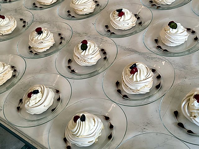 Pavlovas con crema y frutos rojos servidas en platos de vidrio