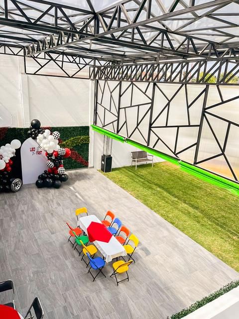 Área techada del salón con una mesa infantil de sillas de colores y el jardín al fondo